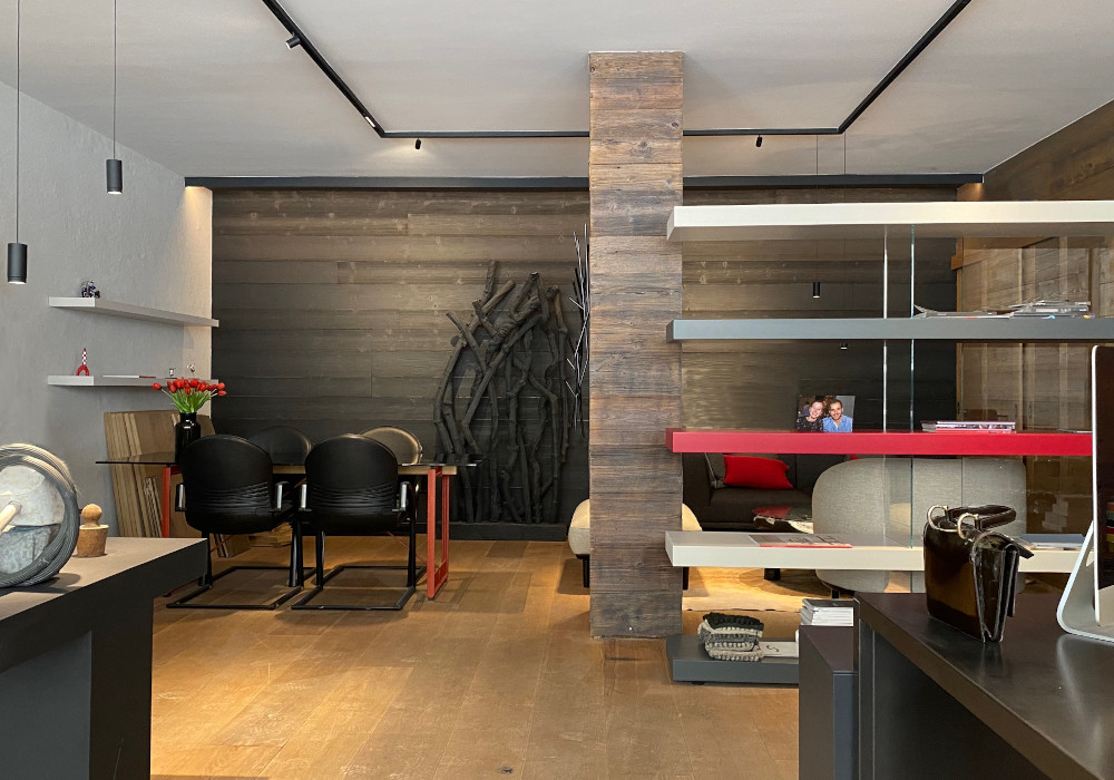 Intérieur du bureau de BDB-architecture à Crans-Montana, avec espace de réunion, étagères design et ambiance chaleureuse en bois.